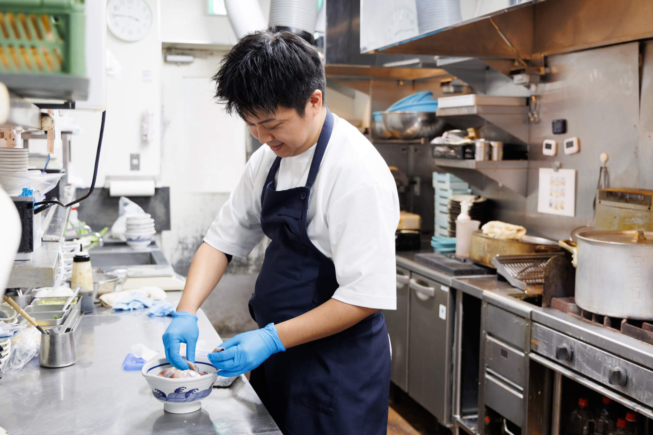 真剣な表情で、一つひとつ丁寧にどんぶりへ盛り付けをする様子