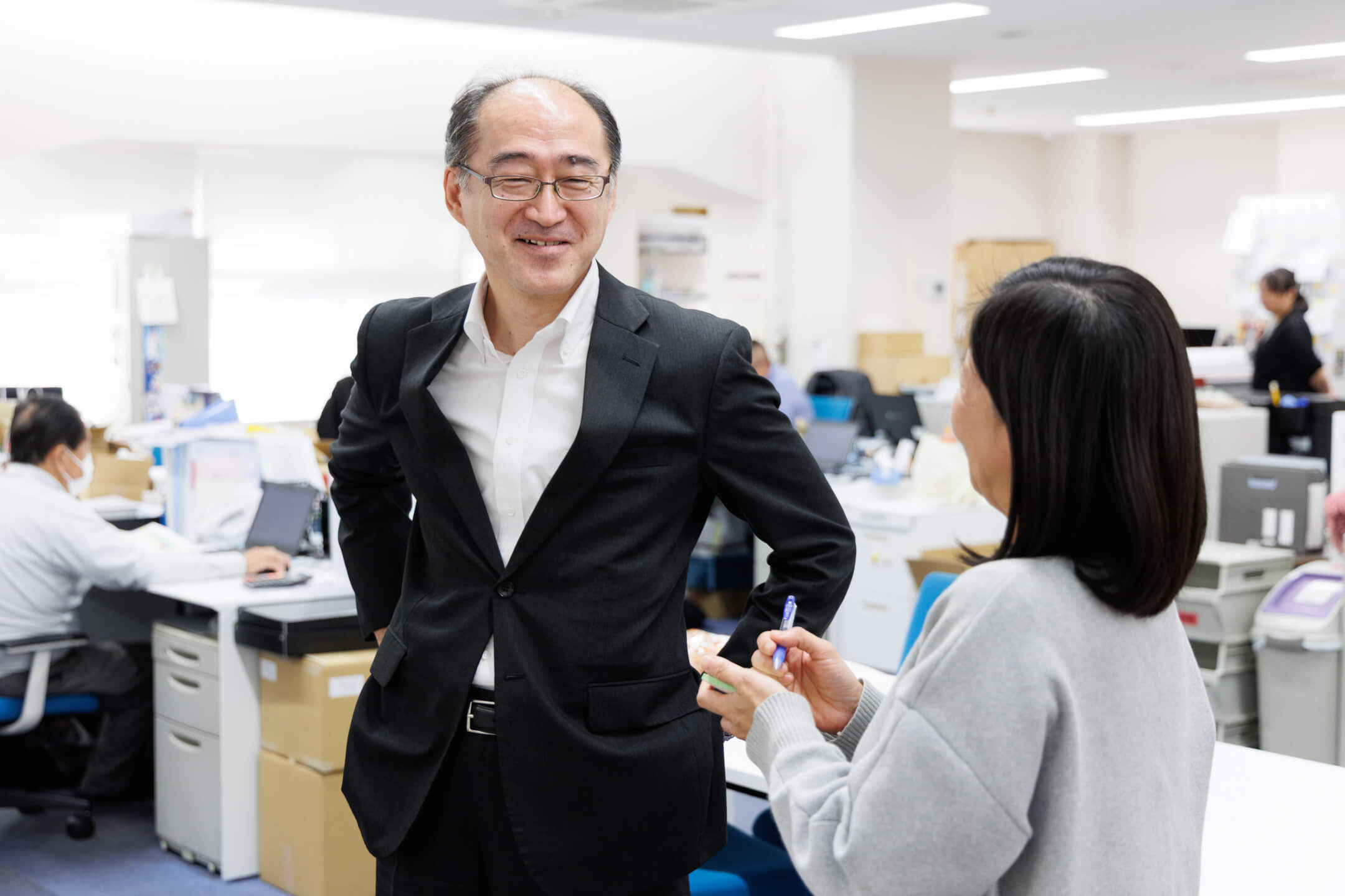 定食が乗ったトレーを手に、柔らかな表情でこちらに視線を向ける様子